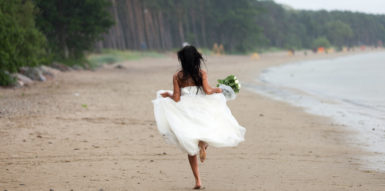 A Bride running down the Beach without any shoes on